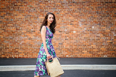 Woman in Purple Floral Dress With Beige Handbag thumbnail