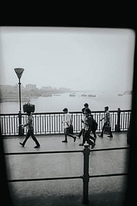 grayscale photography of person walking behind rails thumbnail