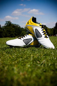pair of white-and-yellow Nike soccer cleats on field during daytime thumbnail