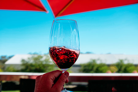 Glass of red wine being held against a blue sky thumbnail