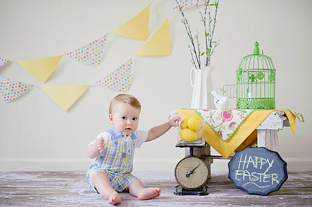baby wearing blue and white rompers sitting beside table thumbnail