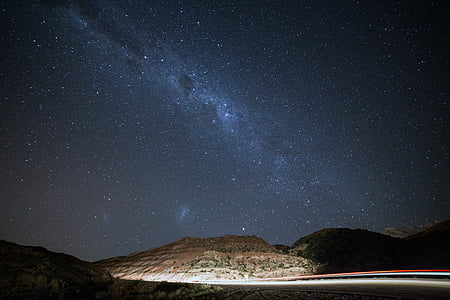 starry night sky over the highway in between hills thumbnail