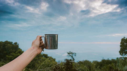 person holding gray stainless steel cup during daytime thumbnail