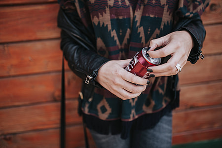 Blonde woman with a can of coke by a wooden wall thumbnail