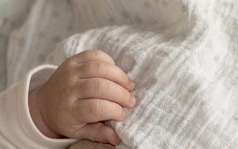 baby's hand touching white textile thumbnail