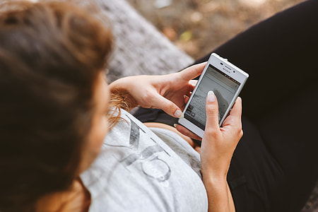 Young woman holding the white mobile phone thumbnail