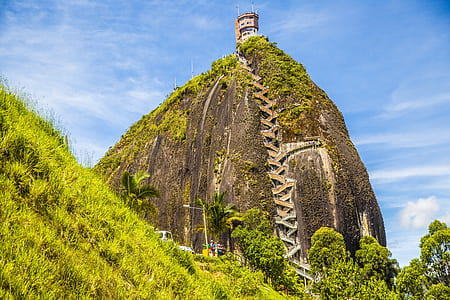 brown concrete building on top of green mountain during daytime thumbnail