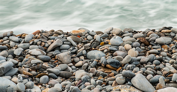 depth of field photography of sea shore pebbles near sea wave thumbnail