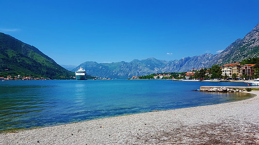 houses in front of ocean water surrounded by mountains covered with green leafed trees during daytime thumbnail