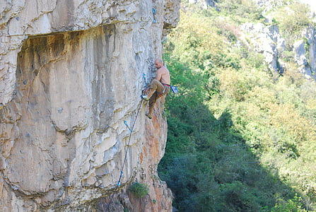 man climbing on cliff during daytime thumbnail