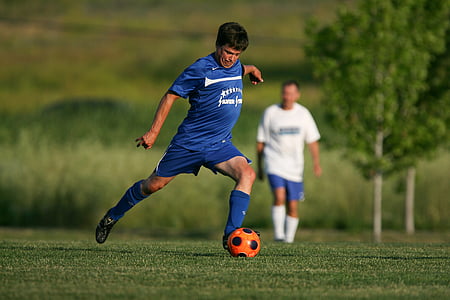 man about to kick the ball on green grass thumbnail