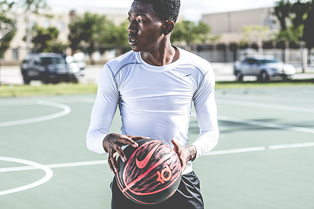 selective focus photography of person on Nike sweatshirt and holding black basketball thumbnail