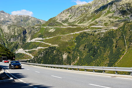 black vehicle passing near hill thumbnail