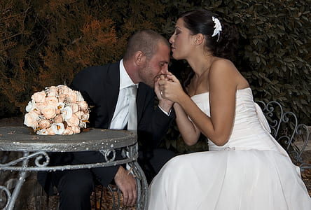 woman wearing white wedding dress while men kissing her hands wearing black suit jacket photograph thumbnail