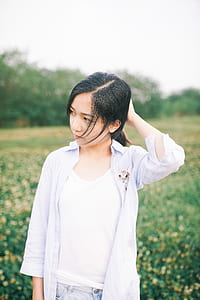 woman in white dress shirt standing behind yellow flowers thumbnail