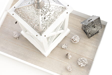 conifer cones beside white candle lantern on wooden deck thumbnail