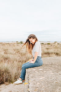 woman sitting on concrete cement surrounded by grass while smiling thumbnail