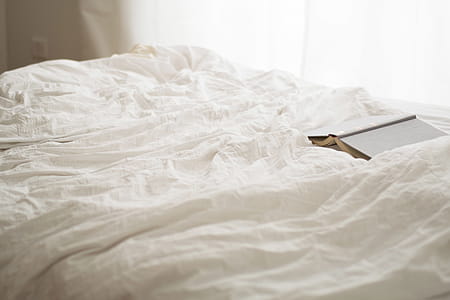 Black and Beige Book on White Bed Sheet thumbnail