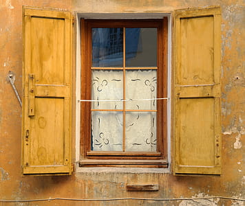 brown concrete building with yellow metal window at daytime thumbnail