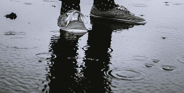 person wearing gray lace-up shoe standing on wet ground thumbnail