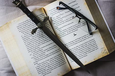 flat-lay photography of eyeglasses, book, and sword thumbnail