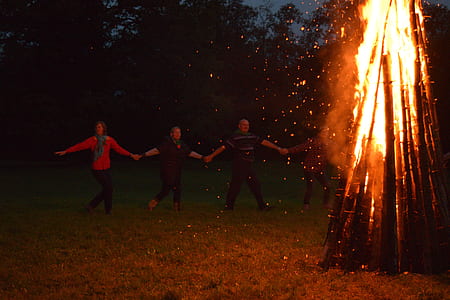 people holding hand each other standing in front of burned wood thumbnail