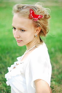 woman wearing white butterfly print top standing on green grass thumbnail
