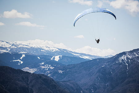 birds eye photography of person with parachute floating above mountains thumbnail