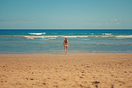 woman standing on seashore during daytime thumbnail