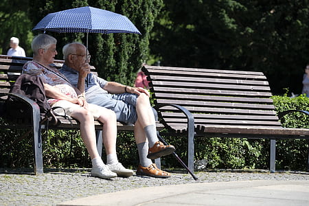man and woman sitting on bench under umbrella thumbnail