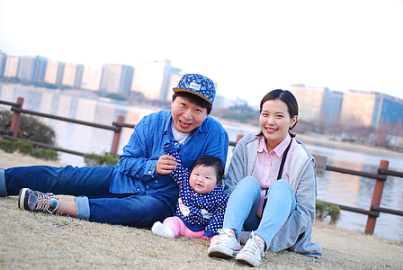 woman with man and child sitting on bank of river during daytime thumbnail