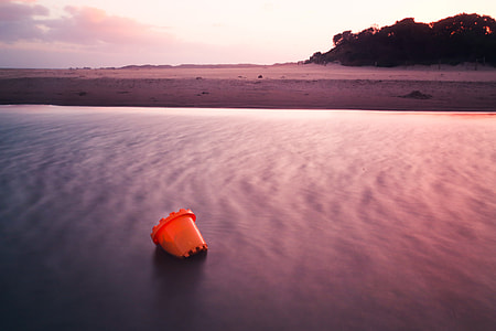 orange plastic bucket on body of water thumbnail