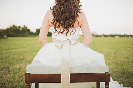 bride seating on bench on field of grass thumbnail