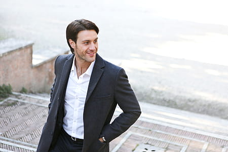A young caucasian man in grey coat posing on a stairway thumbnail