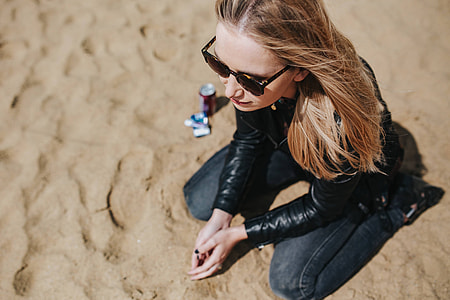 Young woman wearing a leather jacket and sunglasses on the beach thumbnail
