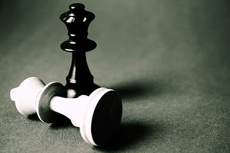 white king chess piece down in front of black king chess piece thumbnail