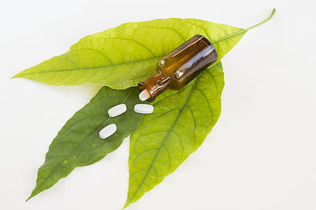four white medicine pills on green leaves thumbnail