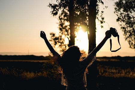 photo of woman raising her hands while holding camera thumbnail