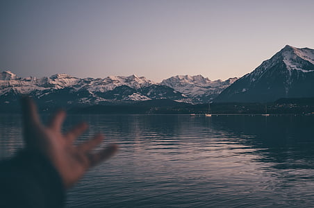 person showing snow covered mountains next to body of water during daytime thumbnail
