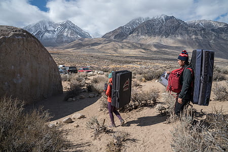 two man and woman carrying hiking backpacks on mountain thumbnail