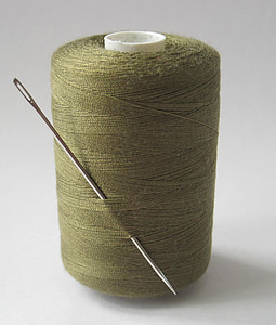 green thread with needle on white surface thumbnail