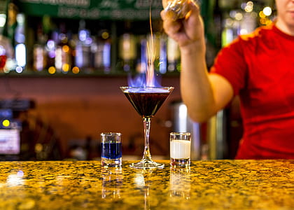 person holding bottle near martini glass filled with drink thumbnail