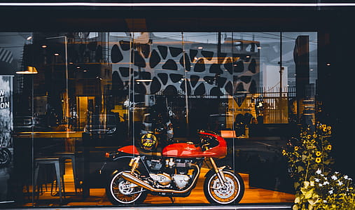 Red Standard Motorcycle With Gold Helmet Near Glass Wall thumbnail