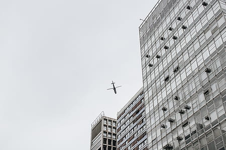 low-angle photography of flying plane near building at daytime thumbnail