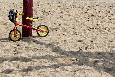 toddler's red and yellow balance bike parked beside post thumbnail