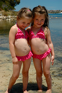two girl standing beside body of water thumbnail