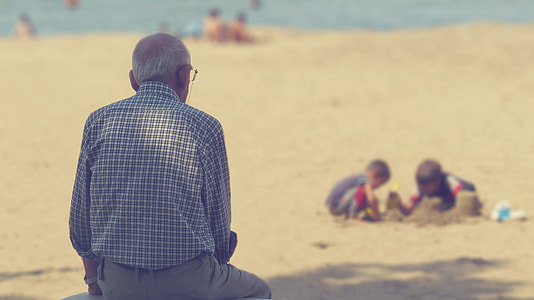 man in blue sport shirt at the beach sitting thumbnail