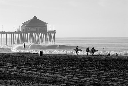 silhouette of surfers carrying surfboards walking at the beach near boardwalk thumbnail