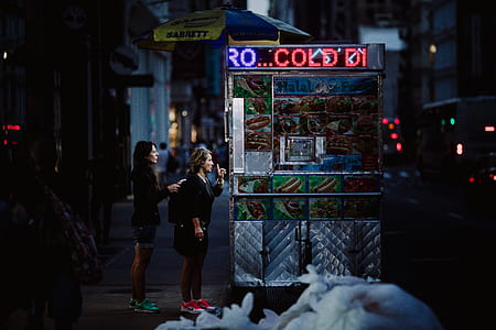 two women standing on food stall during night time thumbnail