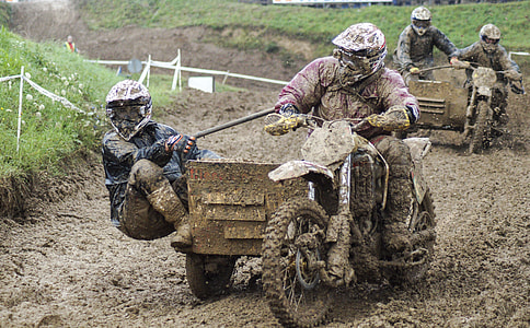 four men riding trikes on muddy ground during daytine thumbnail